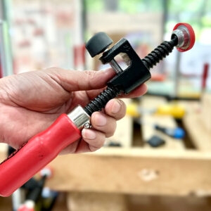 Tay cầm gỗ sơn nước, má kẹp thép mạ kẽm và nắp nhựa bảo vệ bề mặt vật liệu.